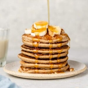 a stack of 3-ingredient vegan pancakes with maple syrup dripping down
