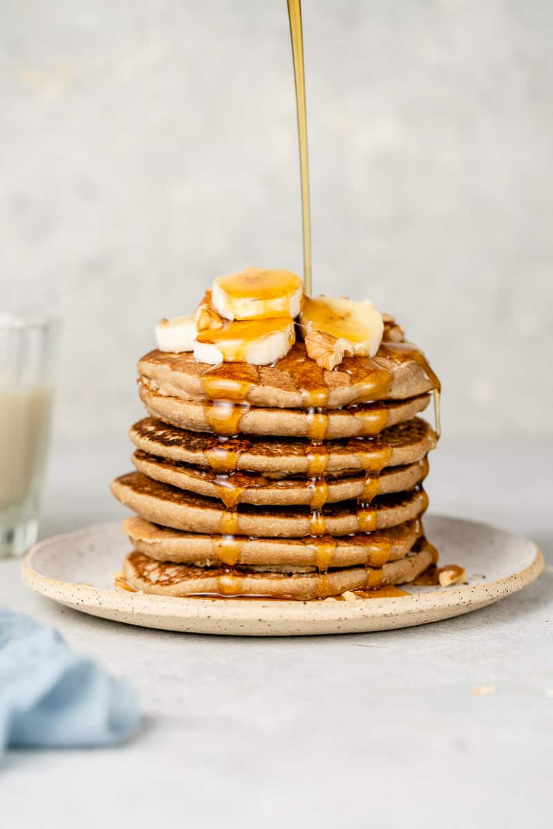 a stack of 3-ingredient vegan pancakes with maple syrup dripping down