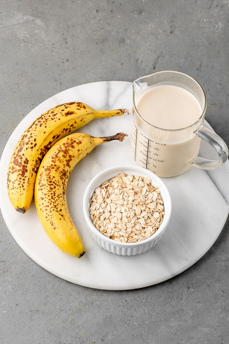 banana, rolled oats and almond milk on a round marble board