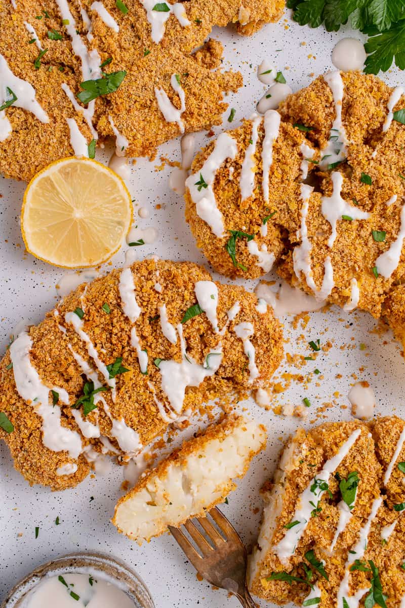 sliced Breaded Cauliflower Steaks on white tray