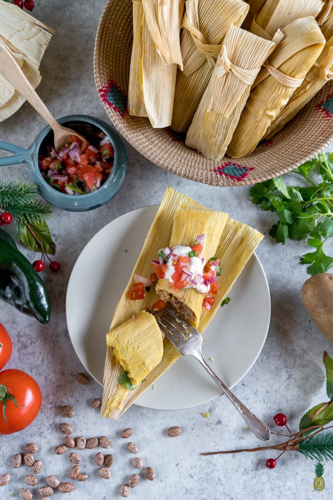 overhead image of tamale on a plate cut with fork.