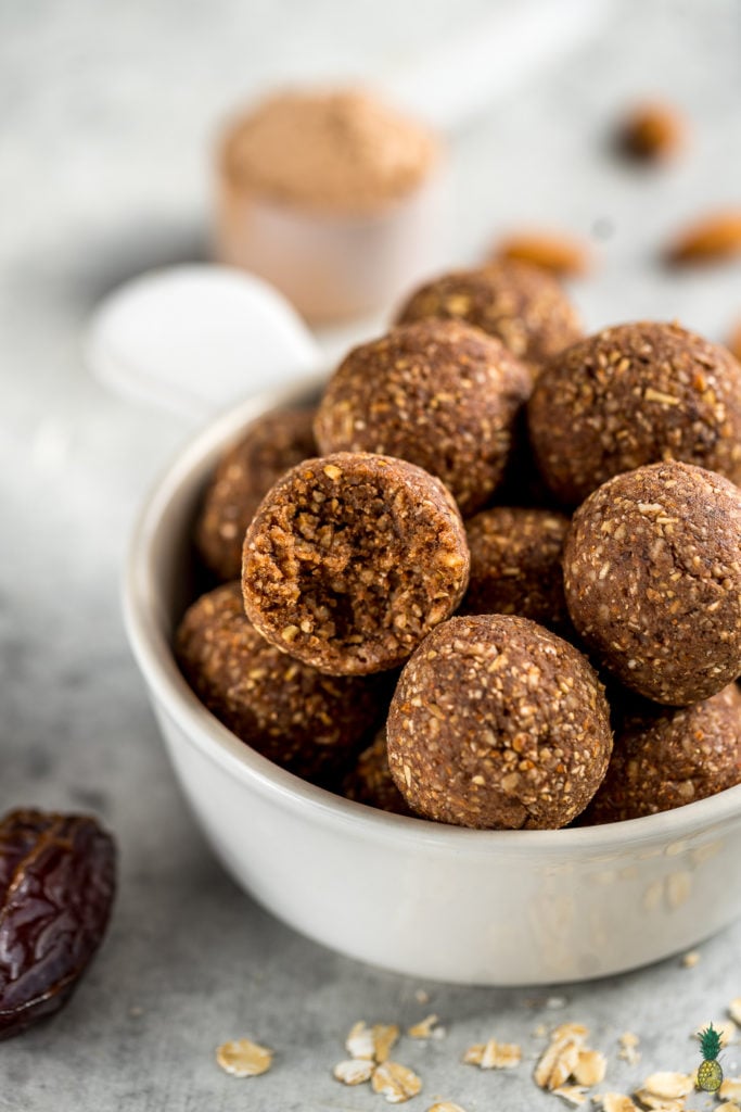 Close-up image of bliss balls in a bowl, one with a bite taken. 