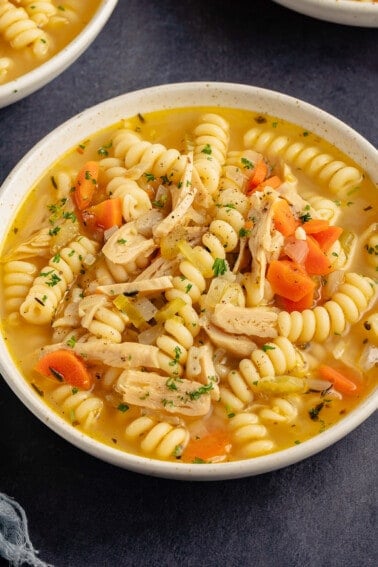close up photo of vegan chicken noodle soup in beige bowl