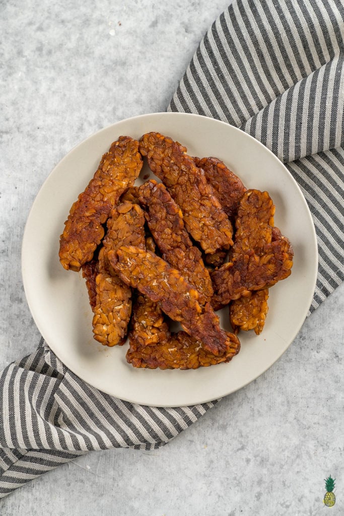 Making tempeh bacon at home is so easy and requires just 8 ingredients! Just whisk everything together, marinate it for a bit and cook it up to perfection. This is the perfect protein packed addition to your next breakfast! #tempeh #bacon #vegan #protein #easy #8ingredient #musttry #homemade #veganbreakfast #veganside #veganbacon #tempehbacon #howto #foolproof #easy