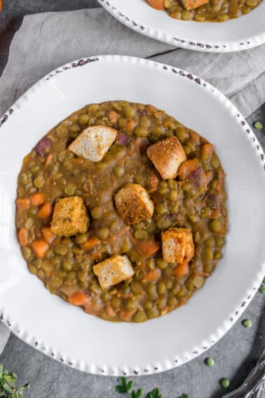 The perfect protein-packed vegan stew for lunch or dinner! THis Hearty Split Pea Stew is loaded with veggies, vegan ham and some homemade bagel croutons that are a must try! #protein #veganprotein #splitpea #vegansoup #veganentree #lunch #dinner #savory #bagel #veggiepacked #musttry #bestvegan #musttryvegan #onthego