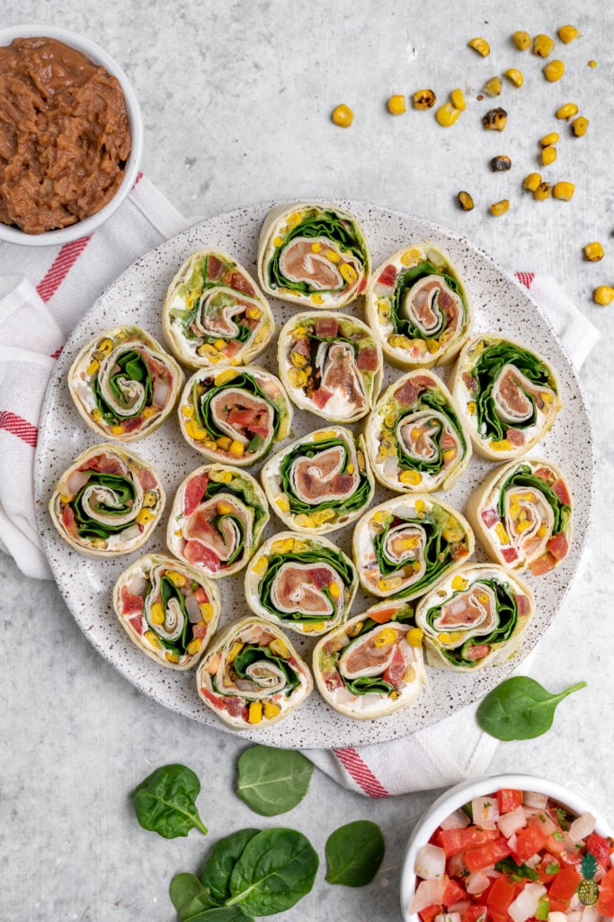 These easy 7-ingredient Mexican-Inspired pinwheels are a must try! They make for the perfect appetizer or lunch and are even great to take on the go! We love bringing these along with our summer picnics and packing them for school lunches. #vegan #appetizer #lunch #summer #picnic #onthego #mexican #inspired #pinwheel #bentobox #lunchbox #veganized #7ingredients