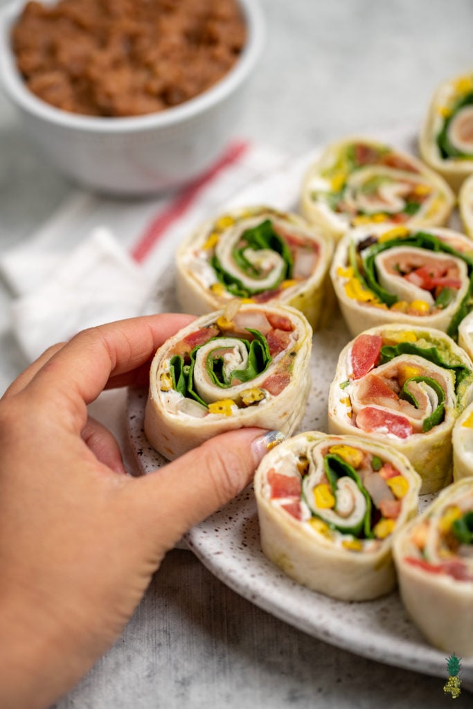 These easy 7-ingredient Mexican-Inspired pinwheels are a must try! They make for the perfect appetizer or lunch and are even great to take on the go! We love bringing these along with our summer picnics and packing them for school lunches. #vegan #appetizer #lunch #summer #picnic #onthego #mexican #inspired #pinwheel #bentobox #lunchbox #veganized #7ingredients