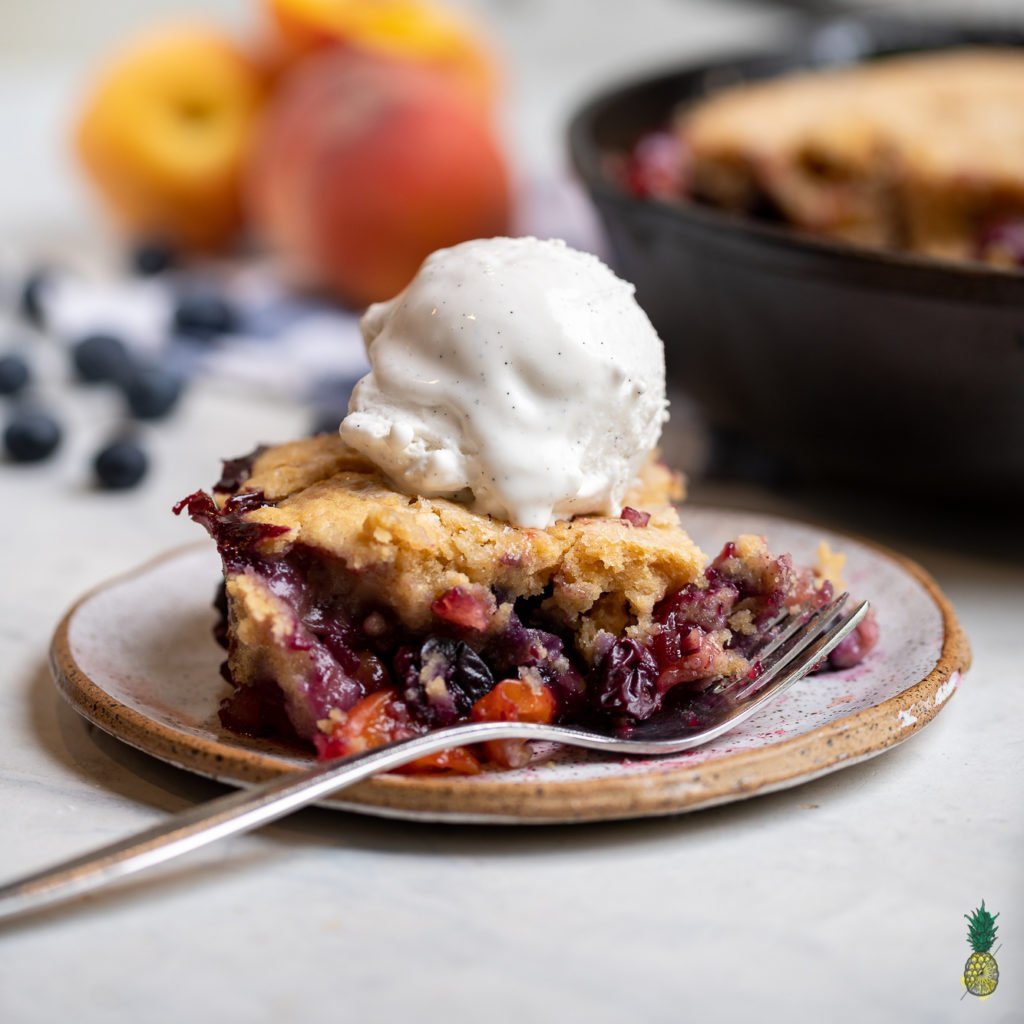 A traditional peach cobbler brought to the next level with the addition of fresh blueberries and 100% plant-based ingredients. The perfect summer dessert ready in about an hour! #cobbler #vegan #veganized #bestofvegan #sweetsimplevegan #letscookvegan #musttry #vegansummerdessert #icecream #easyrecipe #peach #blueberry #cobbler #bakedgoods #easyvegan