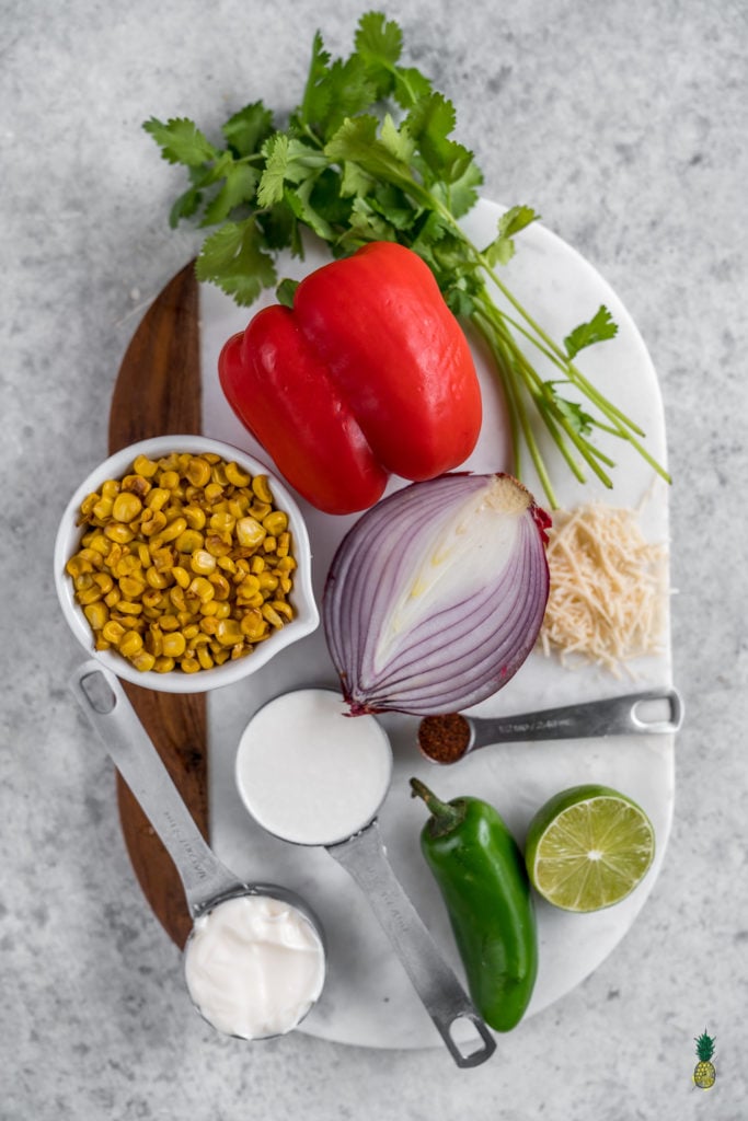 Vegetable ingredients for street corn pasta on a marble board.