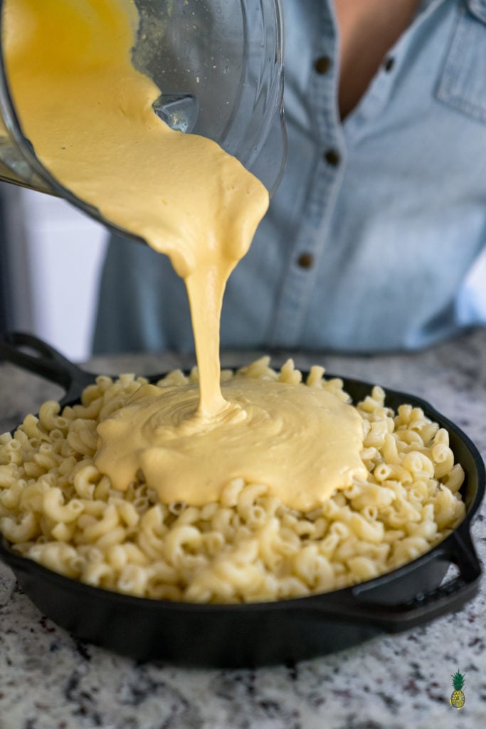 three quarter angle of cheese sauce being poured over pasta