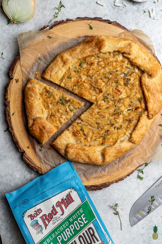 Caramelized onions paired with thyme and vegan cheese, all wrapped in a flaky homemade tart crust. Need I say more? This tart is perfect for entertaining guests and will be the hit of any party! #vegan #onion #tart #savorytart #side #appetizer #party #musttry #easy #veganpastry #veganized #bestofvegan #sweetsimplevegan #caramelized