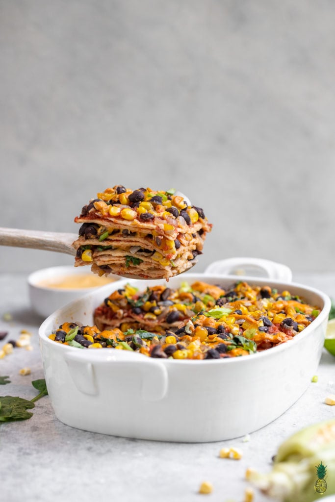 front facing image of enchilada casserole slice being lifted out of dish. 