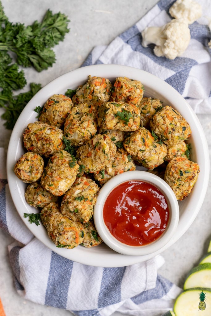 Tater tots taken to a whole new level. Not only do these tots have potatoes, but they are also loaded with zucchini, cauliflower, carrots, onions, and garlic! This recipe is kid-friendly and is the perfect way to pack more vegetables and nutrients into their diets. #kid #kidfriendly #vegankids #hiddenvegetables #tatertots #veggietots #lunch #school #baked #healthy #vegan #sweetsimplevegan #snack #musttry #snackhack #nutritious