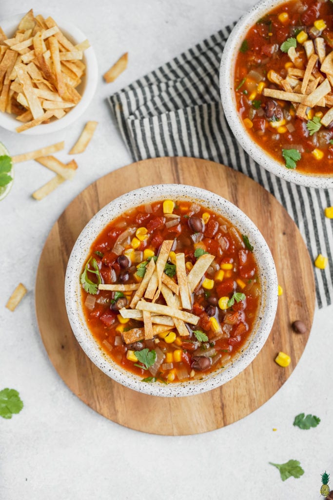 A bowl of vegan tortilla soup with garnishes