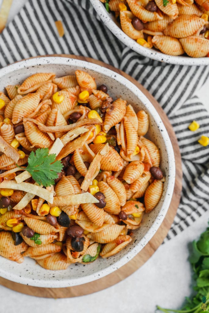 A bowl of taco pasta with a lime and tortilla strips