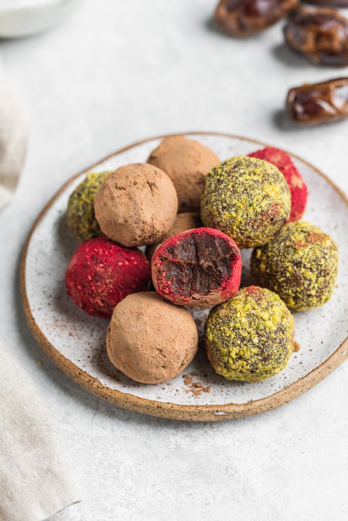 a biten into colorful vegan truffles on a serving plate