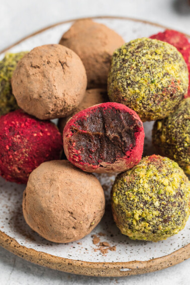 a biten into colorful vegan truffles on a serving plate