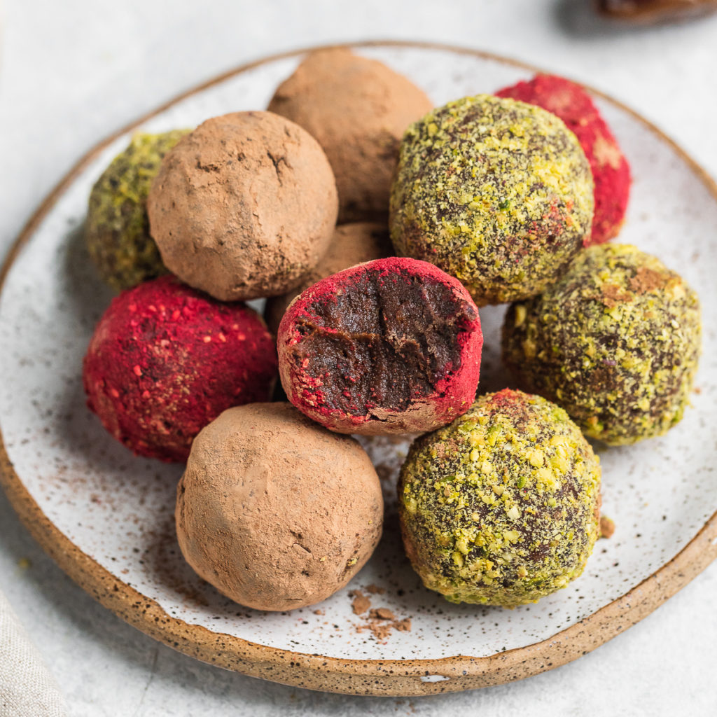 a biten into colorful vegan truffles on a serving plate