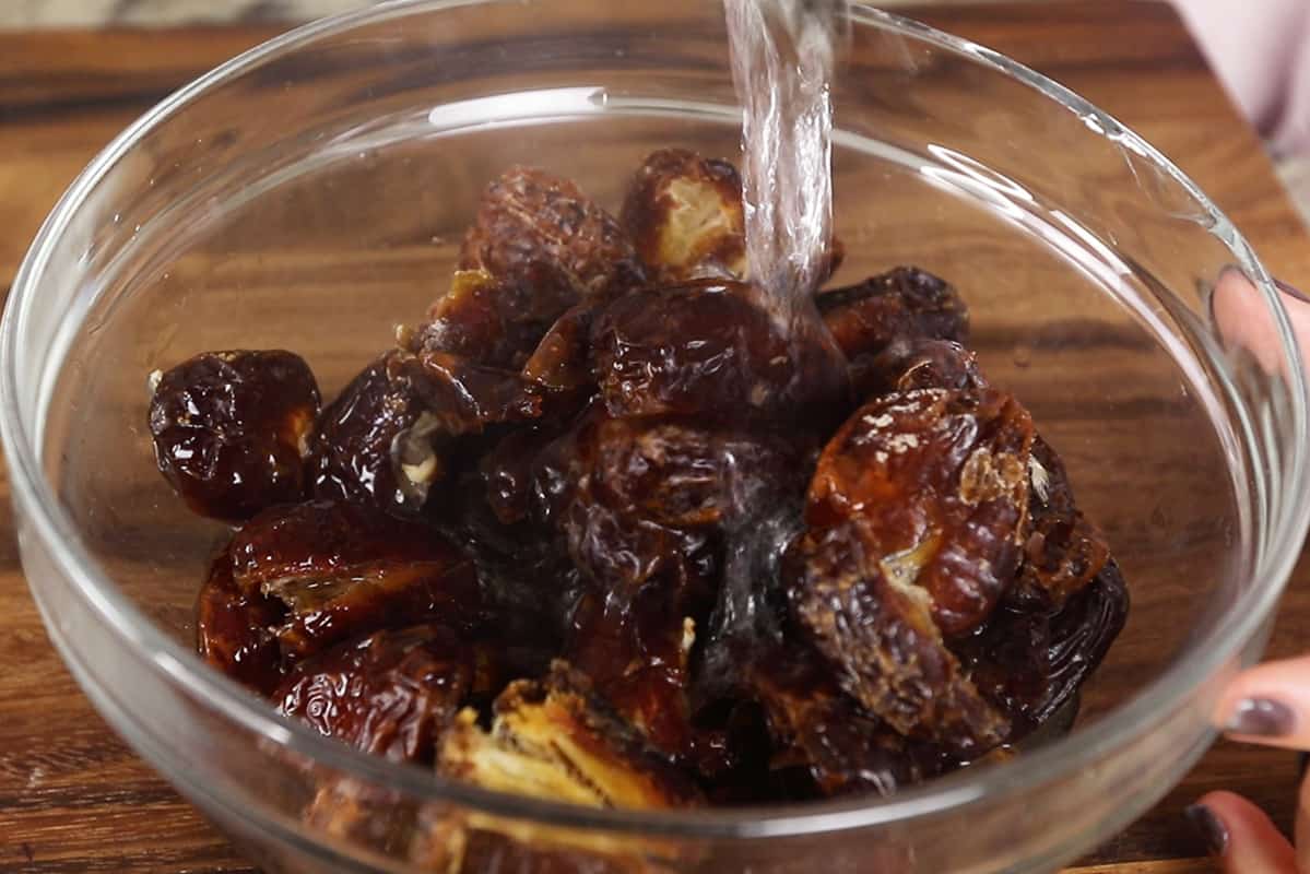 pouring hot water over pitted medjool dates in a glass bowl