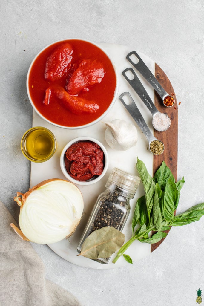 Ingredients for vegan marinara sauce, tomatoes, tomato paste, onions, basil, olive oil, spices