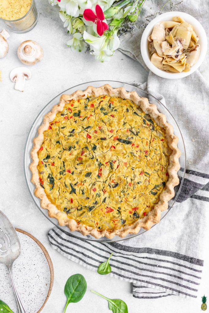 An overhead shot of an uncut vegan quiche with a crimped crust