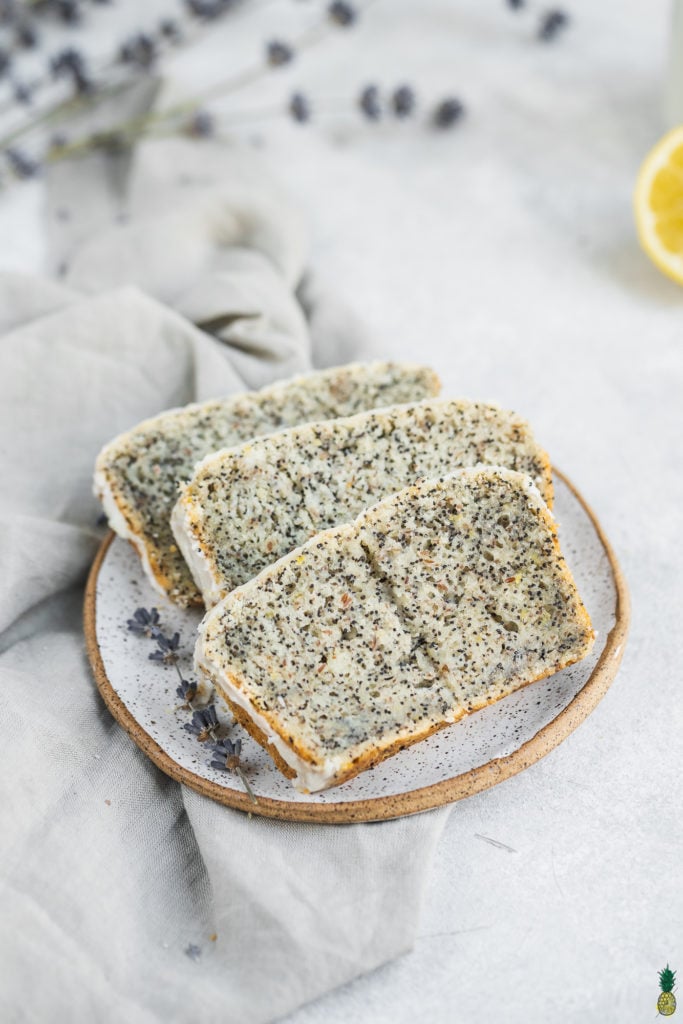 slices of gluten-free vegan lemon poppyseed loaf with a glaze on a plate