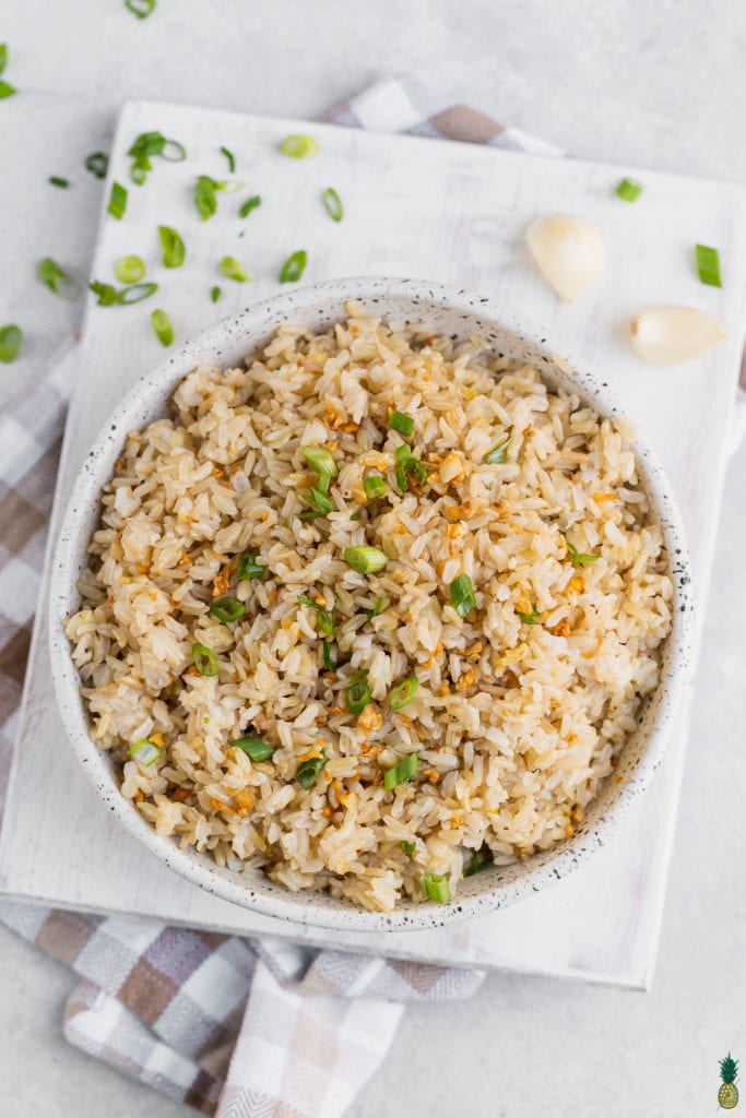 Vegan filipino garlic fried rice in a bowl with green onions and garlic on the side