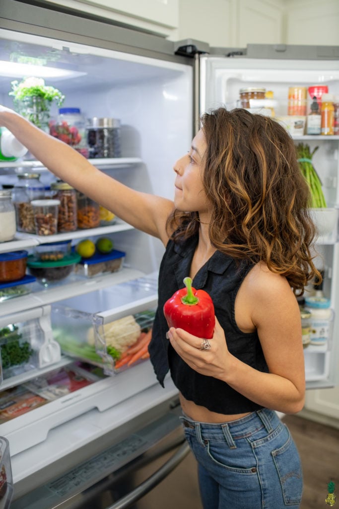 Holding a bell pepper in front of the fridge, vegan fridge tour