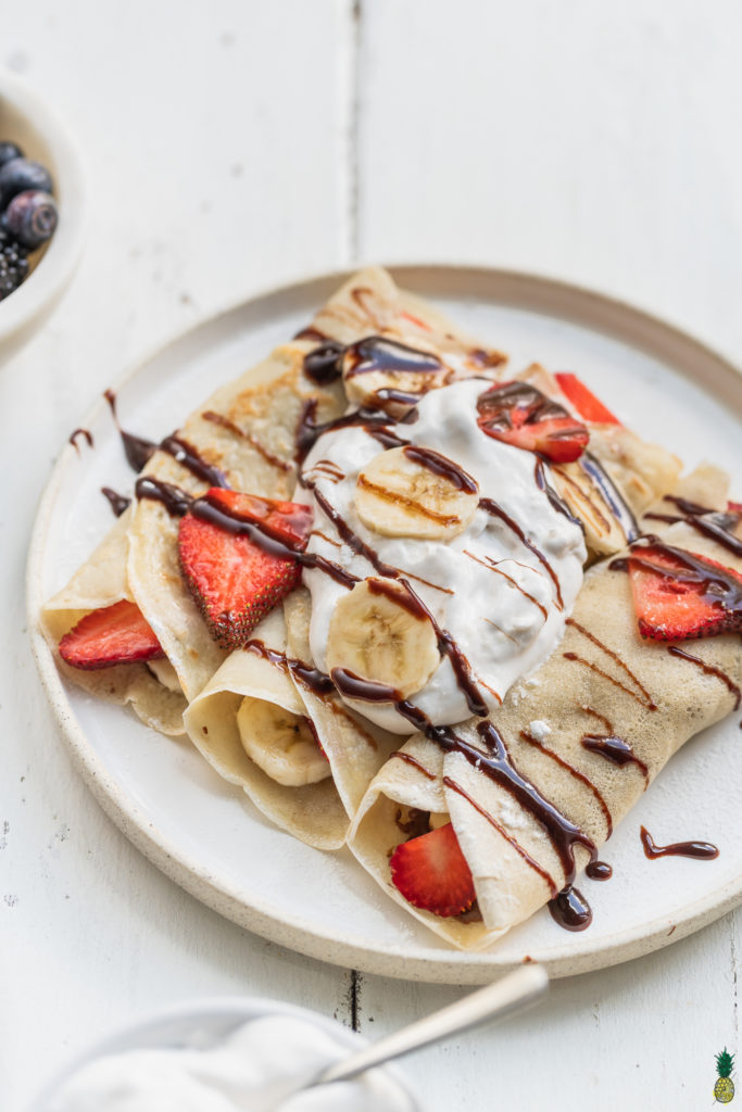 Vegan French Crepes topped with whipped cream, chocolate sauce, fresh fruit and powdered sugar. Sweet Simple Vegan Blog