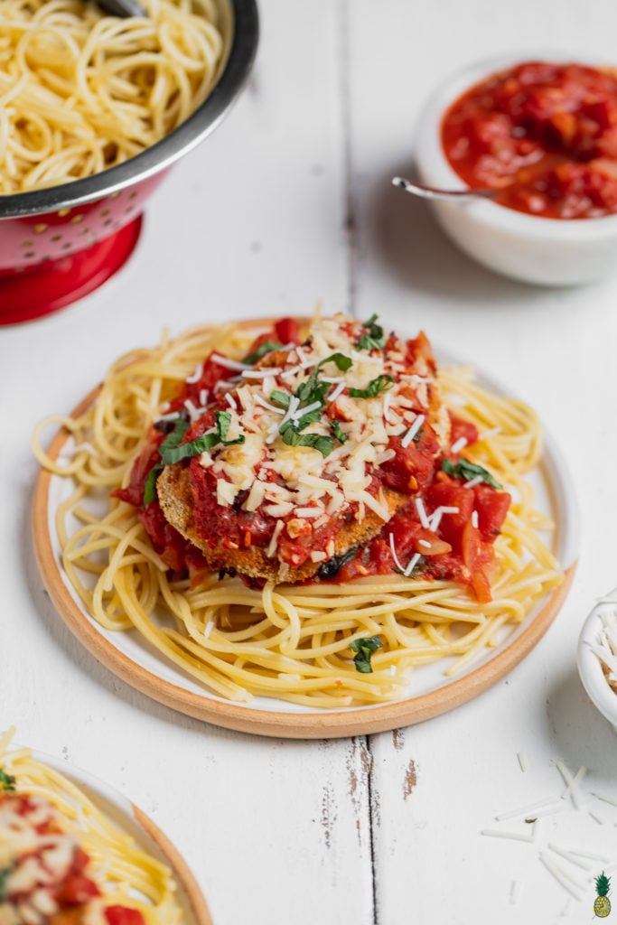Vegan chicken parmesan garnished with basil on a plate with spaghetti, sweet simple vegan blog.