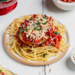 Vegan chicken parmesan garnished with basil on a plate with spaghetti, sweet simple vegan blog.