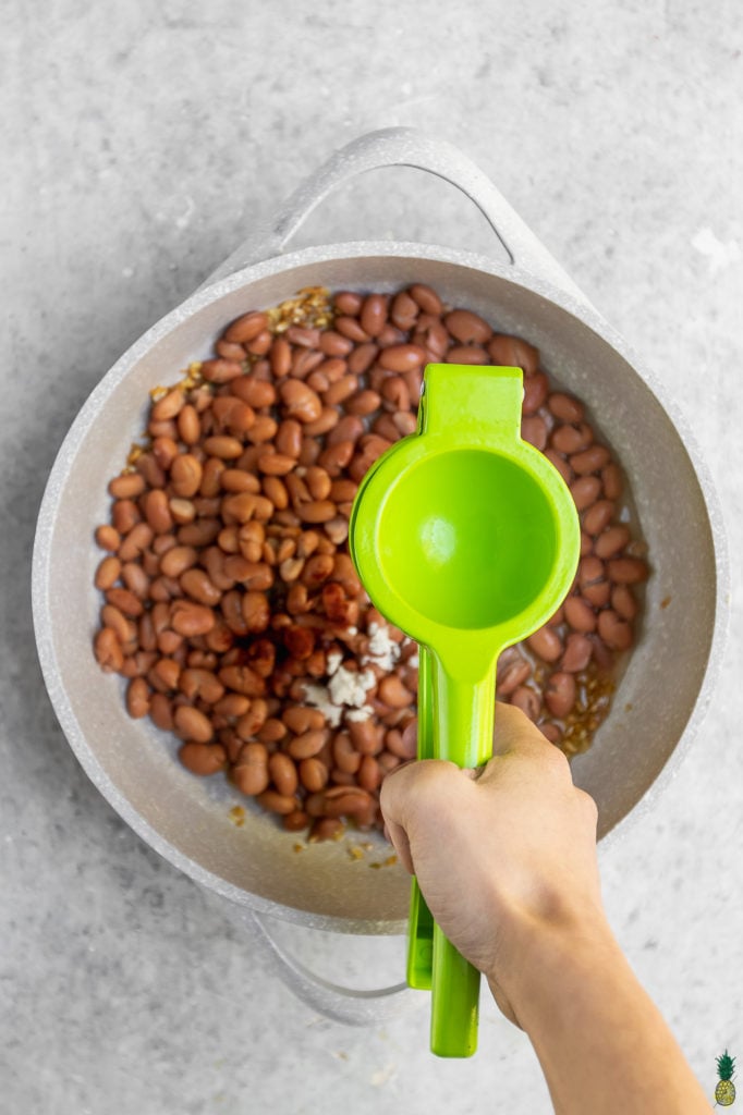 Squeezing lime into a pan of refried beans by Sweet Simple Vegan