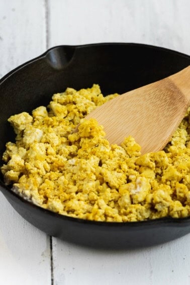 photo of tofu scramble in cast iron skillet with wooden spatula