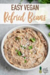 Close up of Simple refried beans in a bowl topped with cheese and cilantro by Sweet Simple Vegan Pinterest image