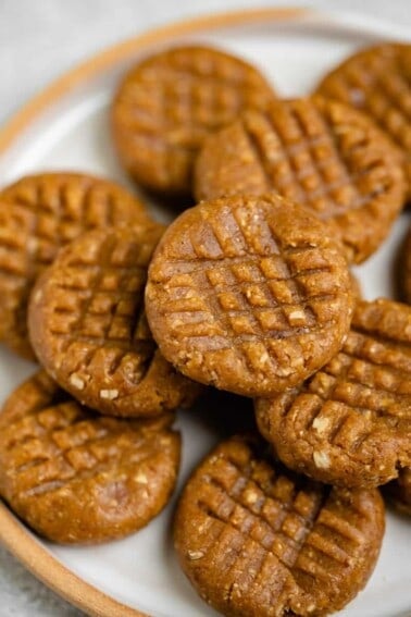 close up photo of no bake peanut butter cookies stacked on white plate