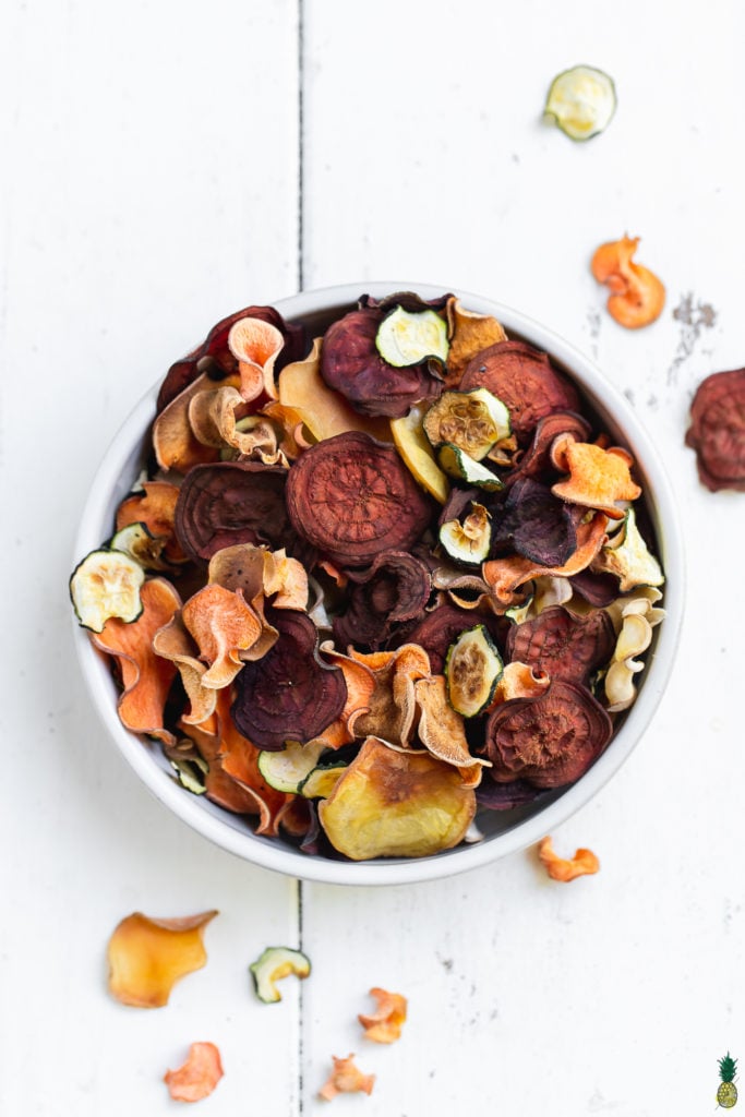 mixed vegetable chips in a bowl on a white background by sweet simple vegan