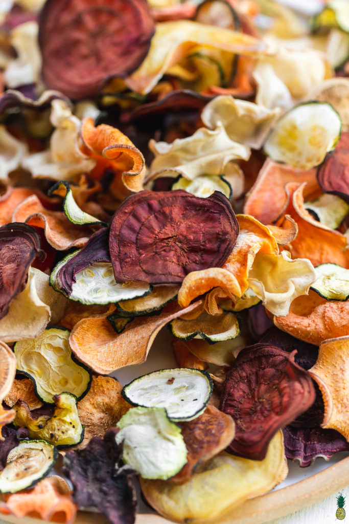 a close up of crispy mixed vegetable chips in a bowl on a white background by sweet simple vegan