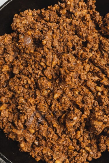 A close up shot of vegan mushroom walnut taco meat in a cast iron skillet by sweet simple vegan