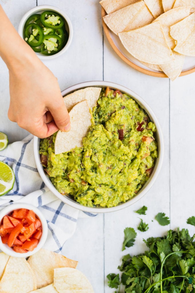 Chip getting dipped into guacamole by Sweet Simple Vegan