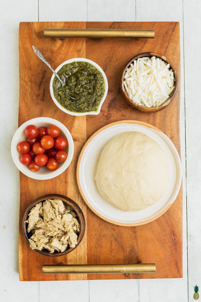 Ingredients for vegan chicken pesto pizza on a wooden board