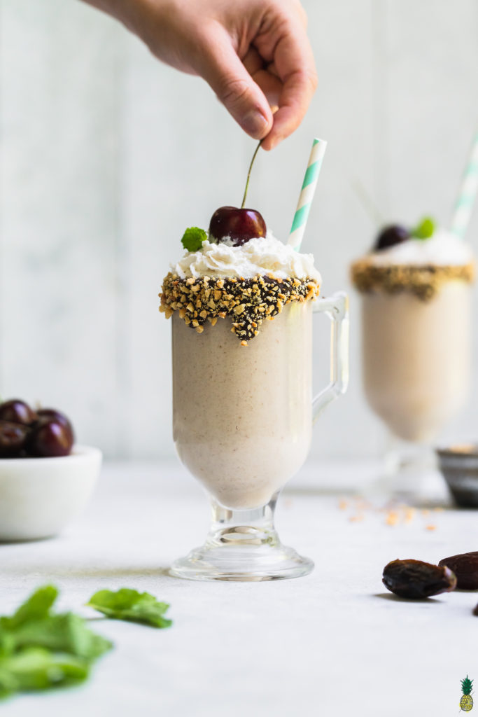 Adding a cherry on top of a date ice cream shake by sweet simple vegan