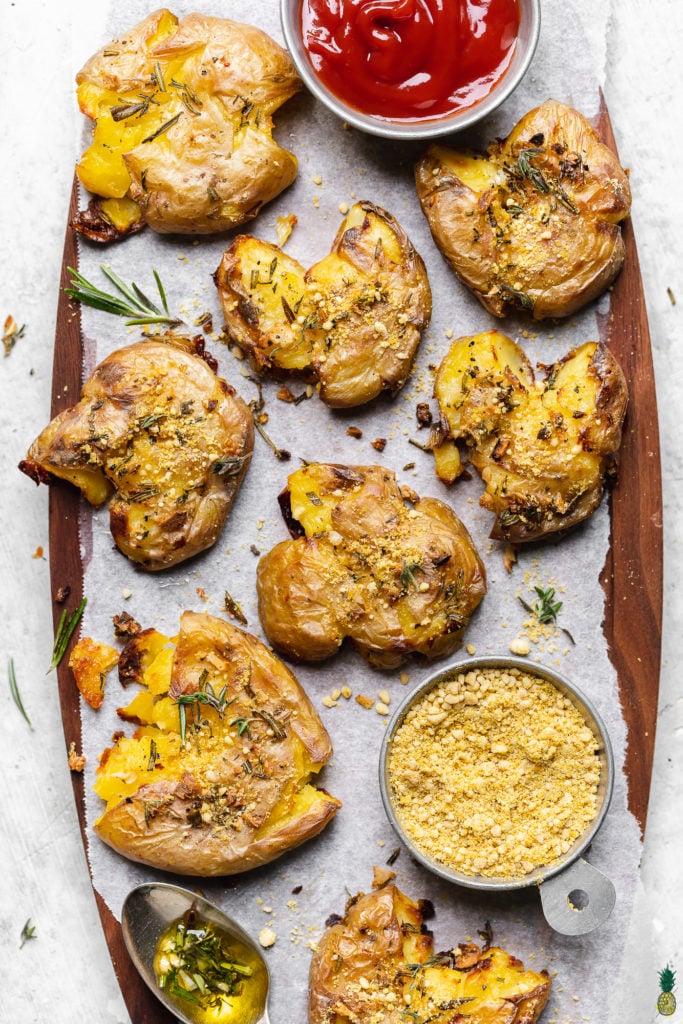 garlic and herb smashed potatoes on a platter with ketchup by sweet simple vegan