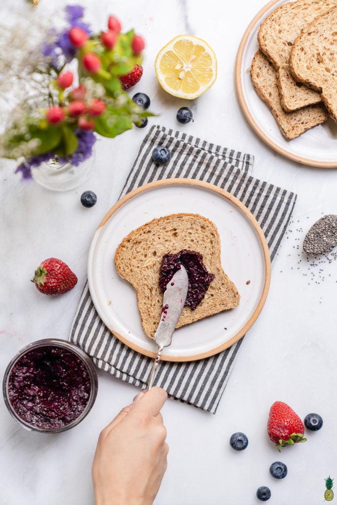 Spreading chia seed jam on a piece of toast by sweet simple vegan
