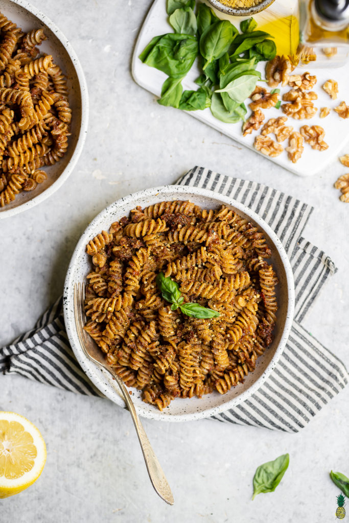 Bowl of vegan sun dried tomato pesto pasta with a towel food photography