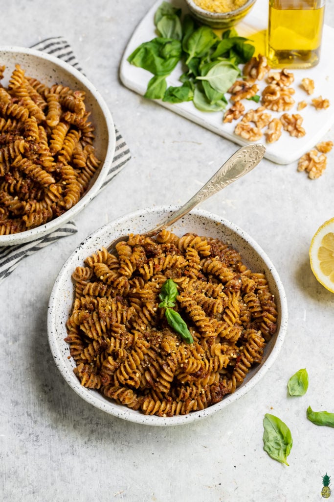 Bowl of vegan sun dried tomato pesto pasta with a towel food photography