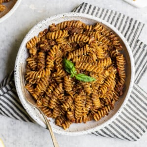 Bowl of vegan sun dried tomato pesto pasta with a towel food photography