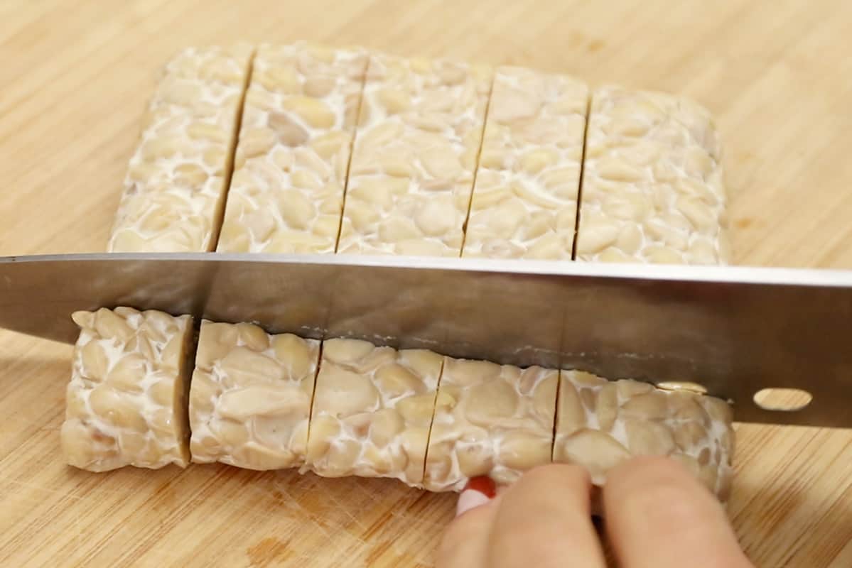 slicing block of tempeh into cubes