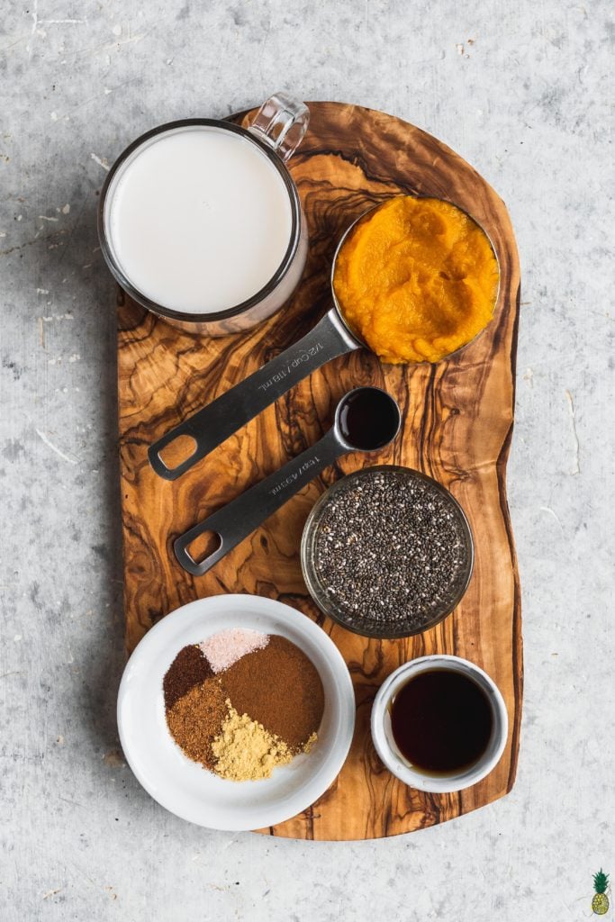 Ingredients for pumpkin pie chia seed pudding on a wooden board by sweet simple vegan