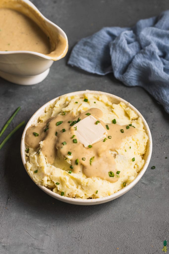 vegan mashed potatoes topped with gravy, chives and a square of butter