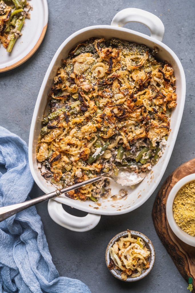  an overhead shot of a vegan green bean casserole with oven baked onions and vegan parmesan cheese